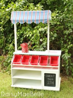 an old fashioned ice cream cart with red cups on it's wheels and a blue awning