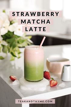 strawberry matcha latte in a tall glass with strawberries next to it on a counter