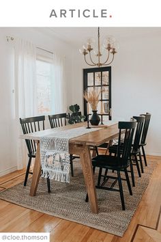 a dining room table with black chairs and a rug on the floor in front of it