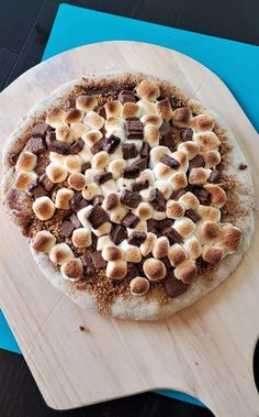 a pizza topped with marshmallows on top of a wooden cutting board