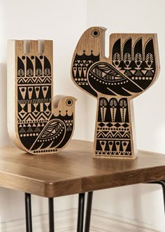 two wooden birds sitting on top of a table