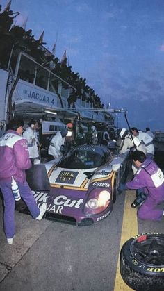 some people standing around a race car on the street