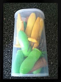 a plastic container filled with green and yellow items on top of a black carpeted floor