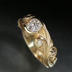 a gold ring with two diamonds in it on a black background and the bottom part of the ring has been made to look like leaves