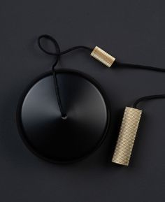 a black surface with a gold colored object on it's side and a cord attached to the top