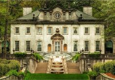 an old mansion with steps leading up to the front door and green grass in front