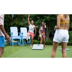 two people are playing frisbee on the grass with chairs in the back ground