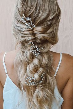 a woman with long blonde hair wearing two braids and some flowers in her hair