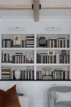 a living room filled with lots of books on top of white shelving unit units