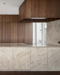 an empty kitchen with marble counter tops and wooden cabinetry on the wall behind it