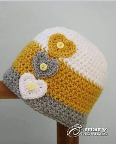 a crocheted hat with flowers on it sitting on top of a wooden pole