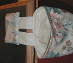 a white hat hanging on the side of a wooden door with flowers and leaves printed on it