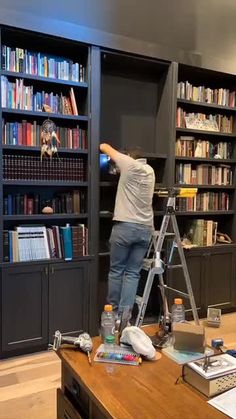 a man standing on a ladder in front of a bookshelf