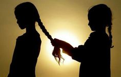 the silhouette of two children holding hands in front of the sun with their hair pulled back