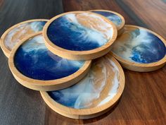 four blue and white plates sitting on top of a wooden table next to each other