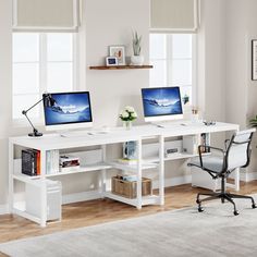 two computer monitors sitting on top of a white desk next to each other in front of windows