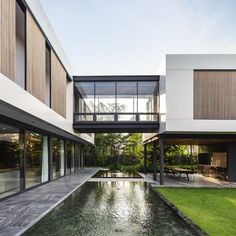 an outdoor area with water, grass and large windows on the side of the building