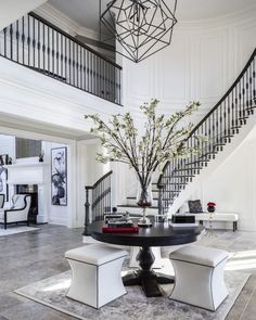 a living room with a table and chairs next to a stair case in front of a fire place