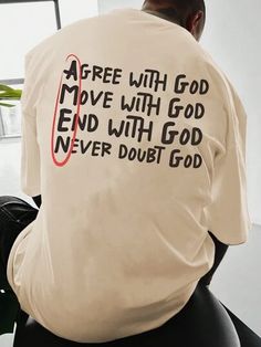 a man sitting in an office chair with his back turned to the camera, wearing a white shirt with black writing on it