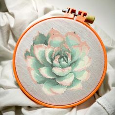 an embroidered succulent sits on top of a white shirt with orange stitching