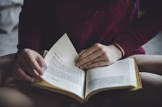 a person sitting down holding an open book