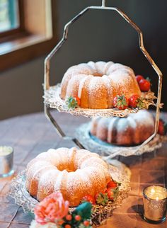 two bundt cakes sitting on top of metal trays next to candles and flowers