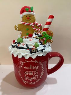 a red mug filled with whipped cream and christmas decorations