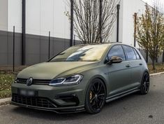 a green volkswagen golf gtr parked on the side of the road in front of a building