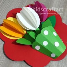 paper flowers are sitting on top of a red flower shaped card with white polka dots