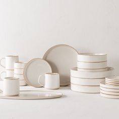 a stack of white plates and cups sitting on top of each other in front of a wall