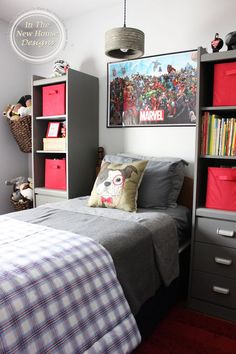 a bedroom with a bed, bookshelf and red bins on the wall