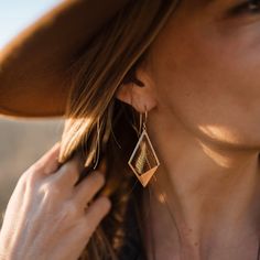 a close up of a person wearing earrings and a hat