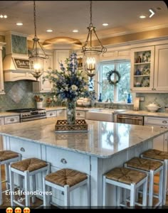 a large kitchen island with stools next to it and lights hanging from the ceiling