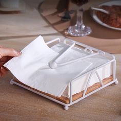 a person holding a napkin holder over a table