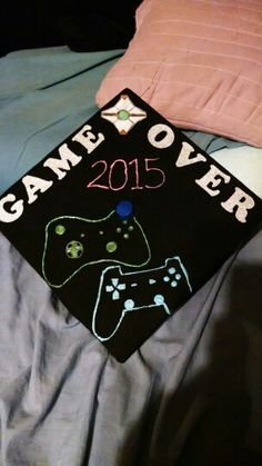 a black graduation cap with game over written on it sitting on top of a bed