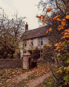 an old stone house surrounded by trees and leaves