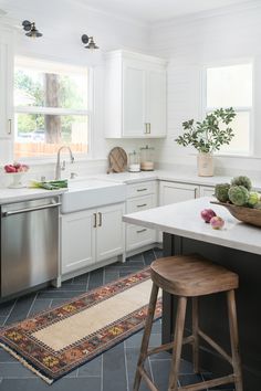 a kitchen with white cabinets and an area rug on the floor next to the sink