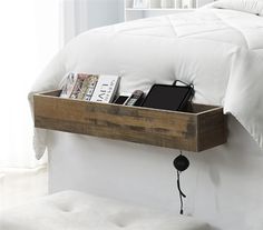 a bed with a white comforter and some books on the shelf next to it