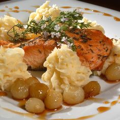 a white plate topped with potatoes and salmon