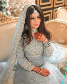 a woman in a blue and white bridal gown sitting on a couch with her hands painted