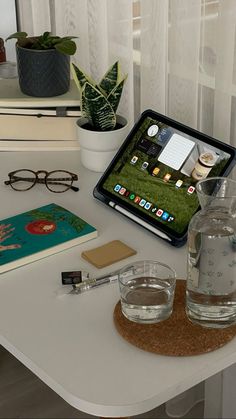 a tablet computer sitting on top of a white table next to glasses and other items