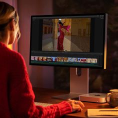 a woman sitting at a desk in front of a computer monitor with an image of a woman on the screen