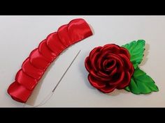 a red rose with green leaves on it next to a piece of thread and scissors