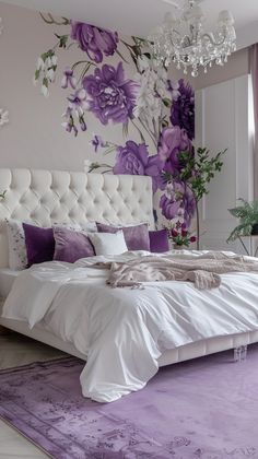 a bedroom with purple flowers painted on the wall and white bedding, along with chandelier