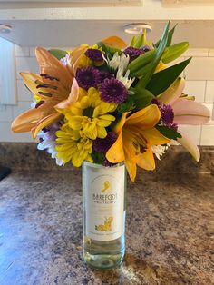 a vase filled with lots of flowers on top of a counter