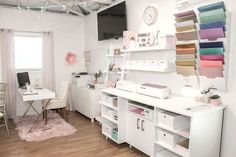 a sewing studio with lots of crafting supplies on the wall and desks in front of it