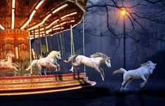 three white horses are on a carousel at night