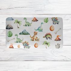 the dinosaurs placemat is on a white wooden surface with wood planks behind it