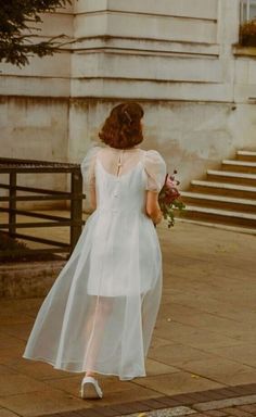 a woman in a white dress walking down the street