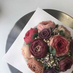 a bouquet of flowers sitting on top of a white paper next to a silver plate